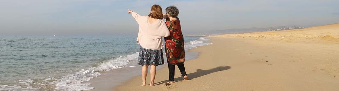 Planificar el Final de La Vida – finaldevida.com En una playa dos mujeres señalan el horizonte - Planificar el Final de la Vida. FinaldeVida.com
