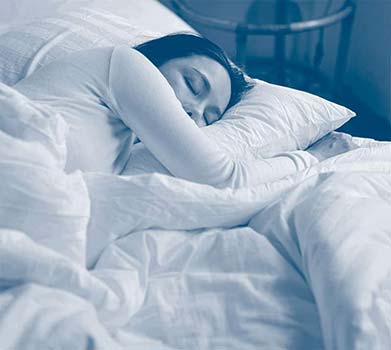Imagen de una mujer dormida en su cama, de costado, descansa durante su proceso con los síntomas de los últimos días de vida.