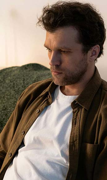 Hombre de mediana edad, con mirada baja, pensando en los dilemas del final de vida.